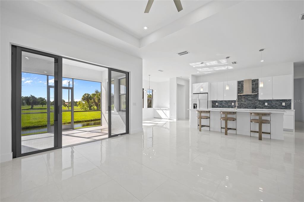 A bright, open-concept kitchen and living area with white tile floors and sliding glass doors — 16322 NOGALES COURT, PUNTA GORDA, FL