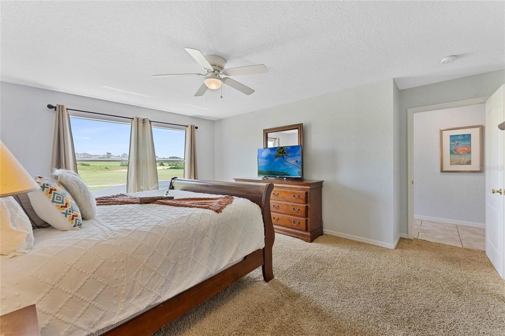 A bedroom features a wooden bed frame, a dresser with a television, and a window — 606 BIRKDALE STREET, DAVENPORT, FL