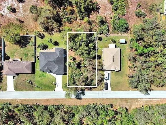 This aerial view shows a vacant, wooded lot outlined in white between two residential houses — 205 FERDON CIRCLE, PORT CHARLOTTE, FL