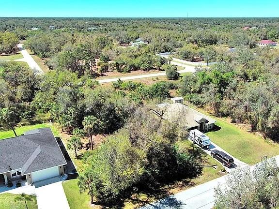 An aerial view shows two houses surrounded by dense trees and vegetation near a road — 205 FERDON CIRCLE, PORT CHARLOTTE, FL