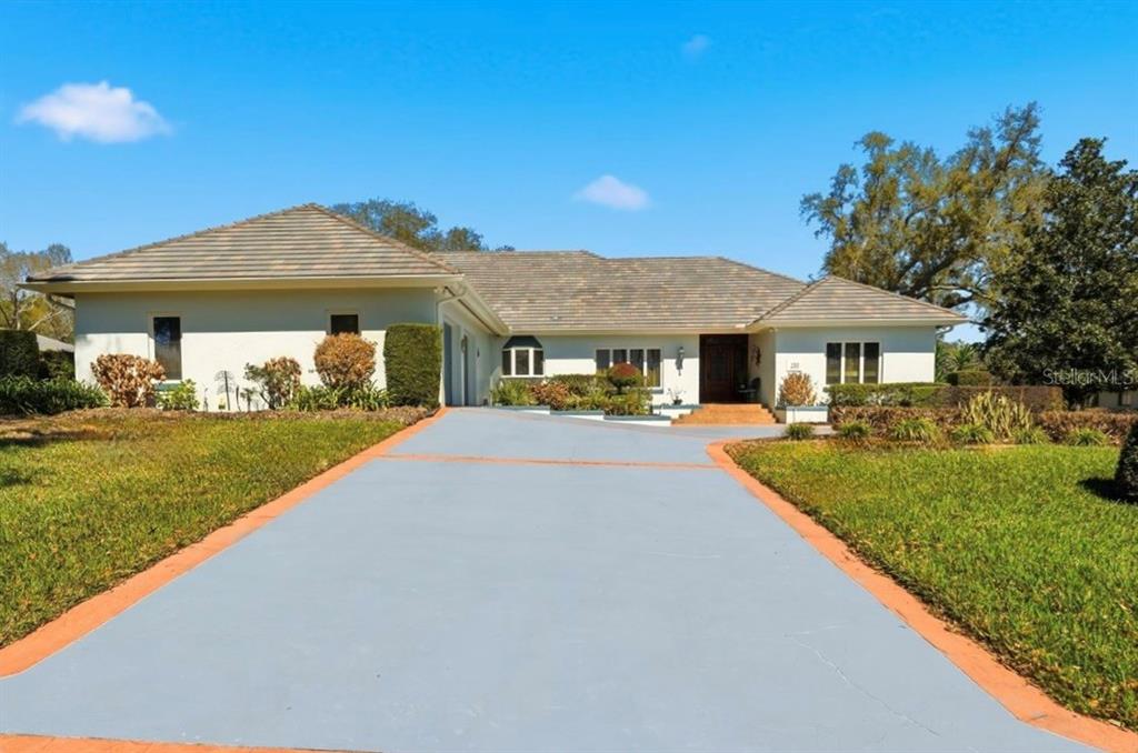 A single-story house with a light-colored exterior, a tiled roof, and a paved driveway — 133 ARROWHEAD LANE, HAINES CITY, FL