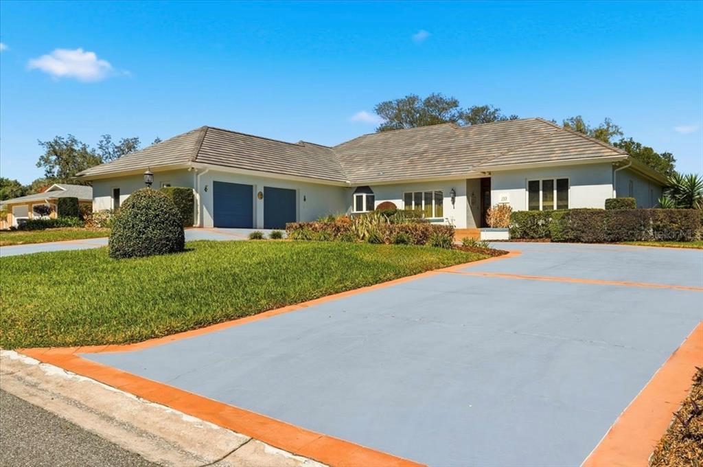 A single-story house with a blue-painted driveway, two-car garage, and a tiled roof — 133 ARROWHEAD LANE, HAINES CITY, FL