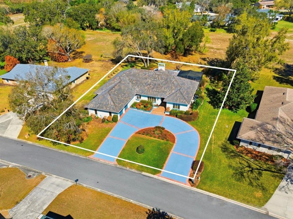 An aerial view of a house with a blue circular driveway and a tiled roof — 133 ARROWHEAD LANE, HAINES CITY, FL