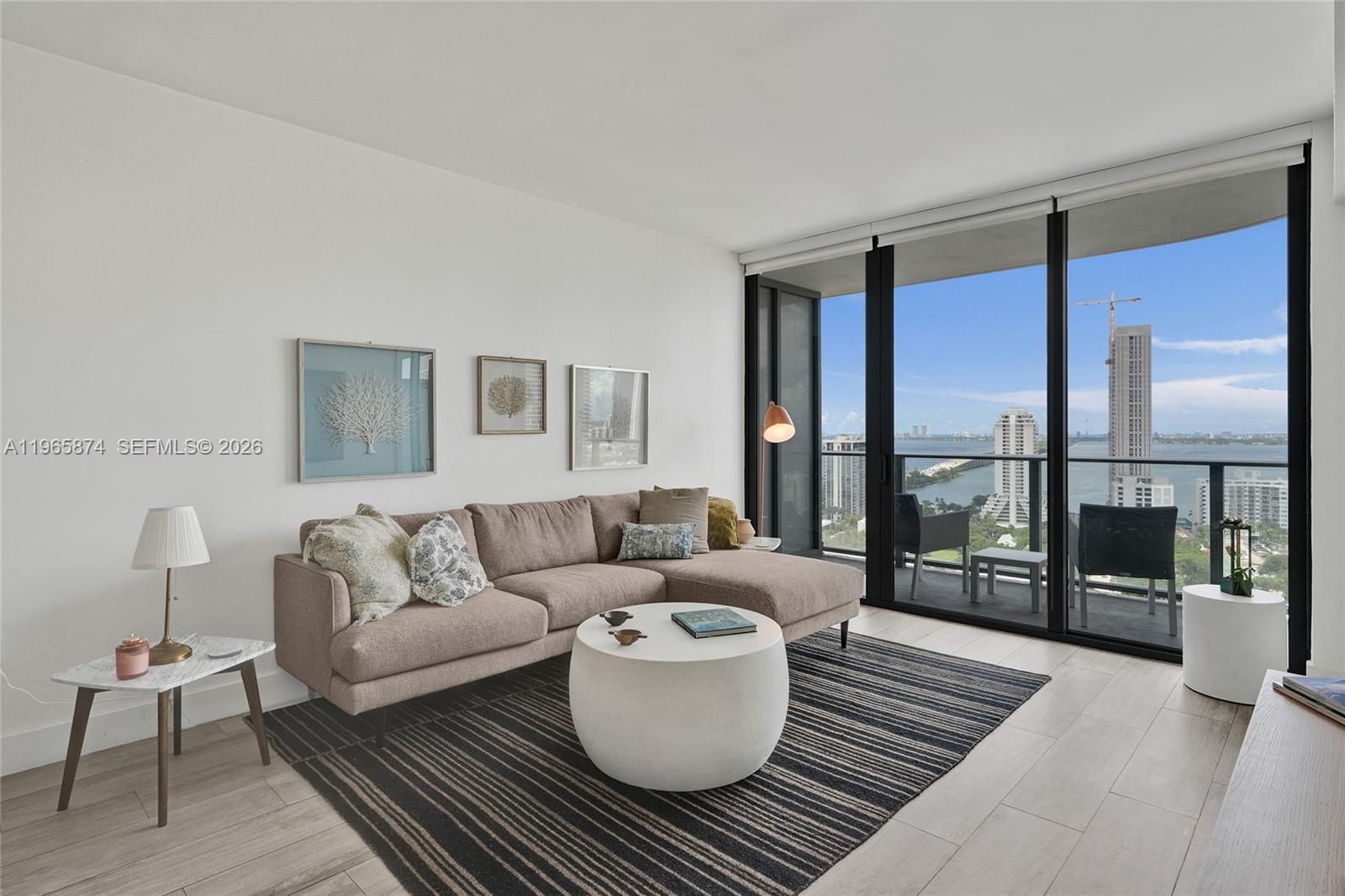 A living room features a sectional sofa, a round coffee table, and floor-to-ceiling windows — 121 NE 34th St # 2205, Miami FL 33137, MIAMI, FL