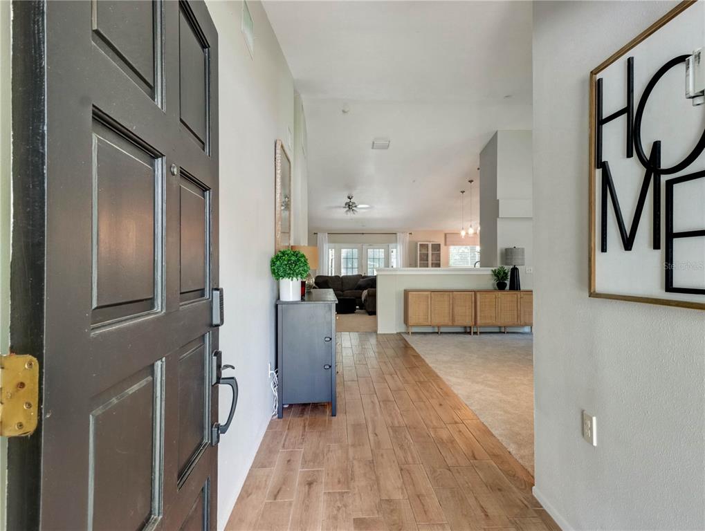 A view from an open front door into a home with wood-look tile flooring — 12004 STEPPINGSTONE BOULEVARD, TAMPA, FL
