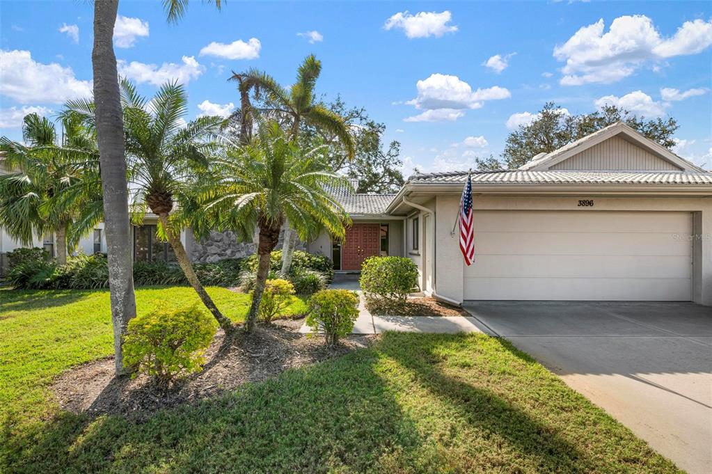 A single-story house with a two-car garage, palm trees, and a stone-accented front facade — 3896 WILSHIRE DRIVE UNIT 11, SARASOTA, FL