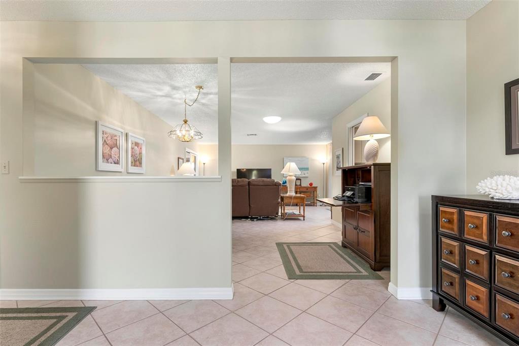 A view through a wide opening into a living room with tiled floors and furniture — 3896 WILSHIRE DRIVE UNIT 11, SARASOTA, FL
