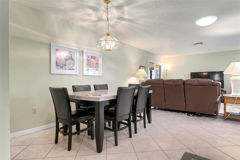 A dining area with a table and chairs sits adjacent to a living room space — 3896 WILSHIRE DRIVE UNIT 11, SARASOTA, FL