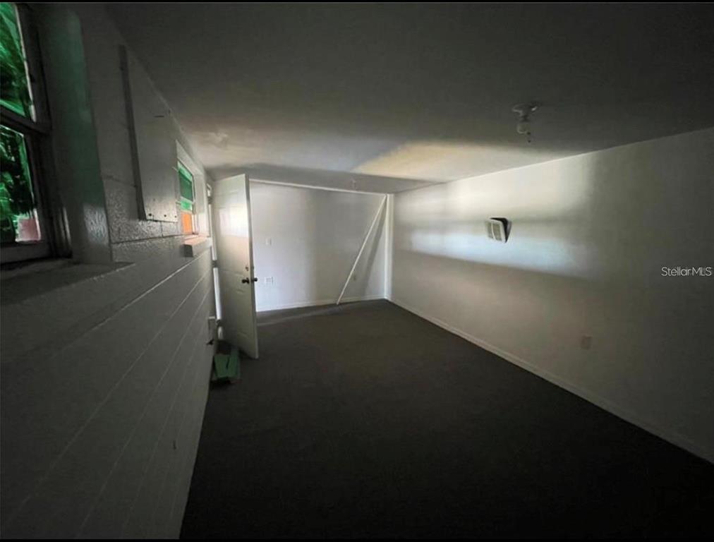 An interior view of a room with gray carpet, white walls, and a single door — 1614 9TH STREET W, BRADENTON, FL