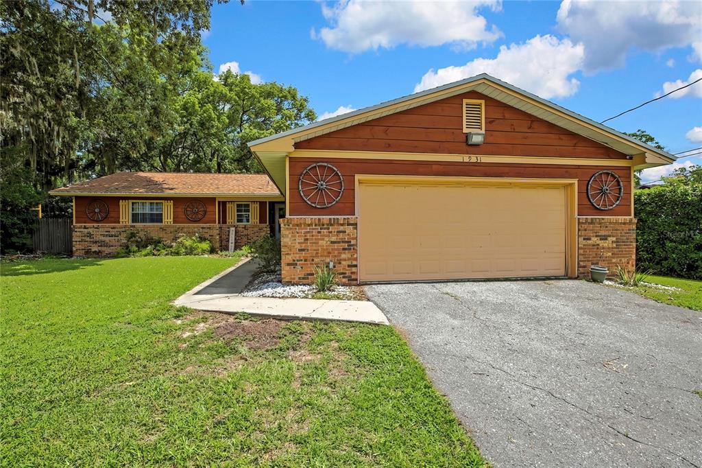 A single-story house with wood siding, brick accents, a two-car garage, and wagon wheel decorations — 1931 SE 39TH STREET, OCALA, FL