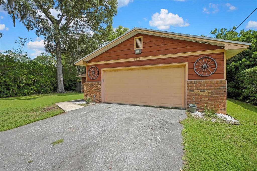 A detached garage with wood siding, brick accents, and decorative wagon wheels on the exterior — 1931 SE 39TH STREET, OCALA, FL