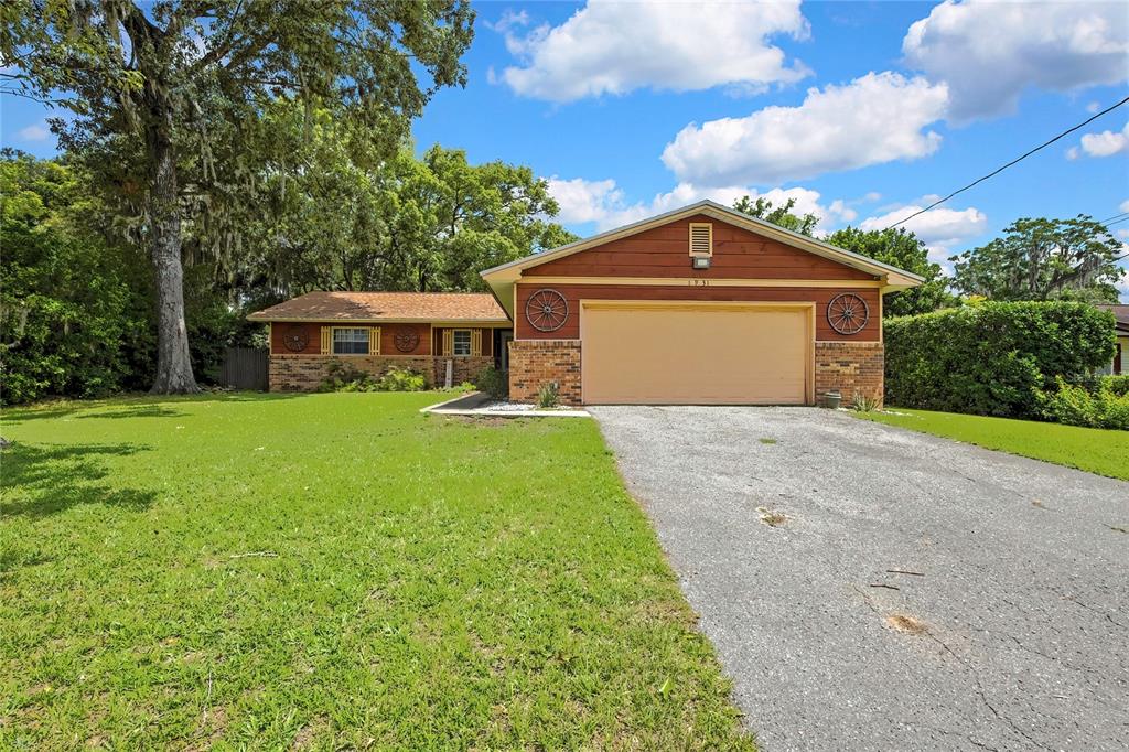 A single-story brick and wood-sided house features wagon wheel decor and yellow window shutters — 1931 SE 39TH STREET, OCALA, FL