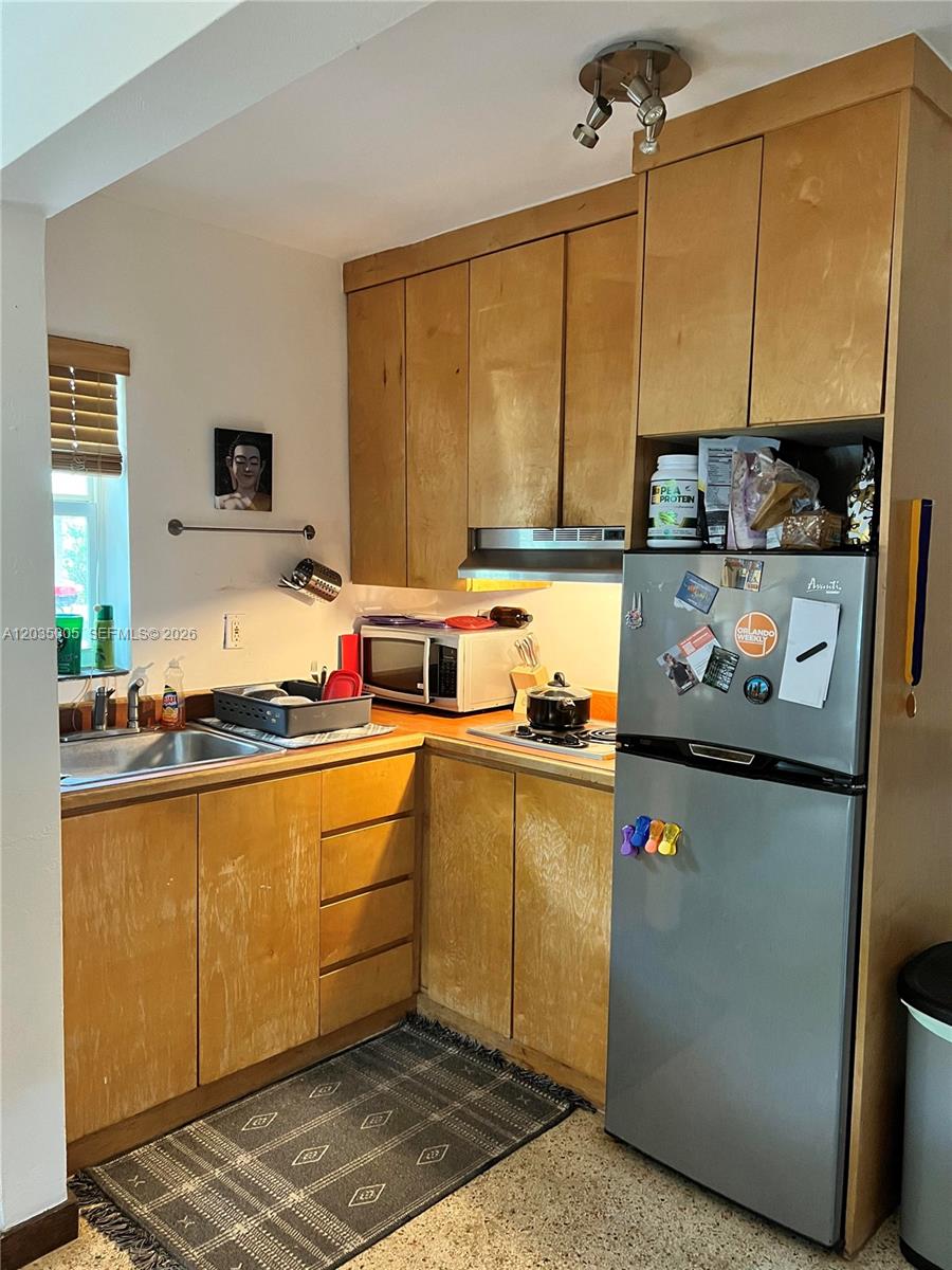 A small kitchen features light wood cabinets, stainless steel appliances, and a patterned area rug — 8845 NE 8TH COURT # 2, Miami FL 33138, MIAMI, FL