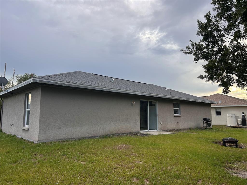 The exterior of a gray stucco house features a sliding glass door and a lawn — 2514 AFFINITY LANE, NORTH PORT, FL