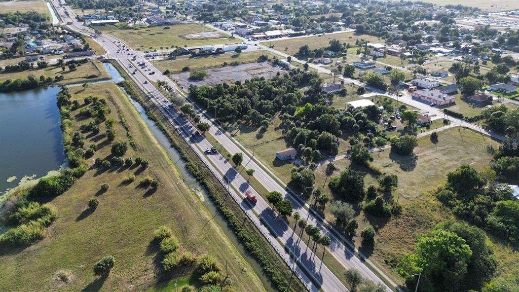 An aerial view shows a road running alongside a canal, trees, and nearby residential buildings — 3550 S GRIMSLEY COURT, FORT MYERS, FL