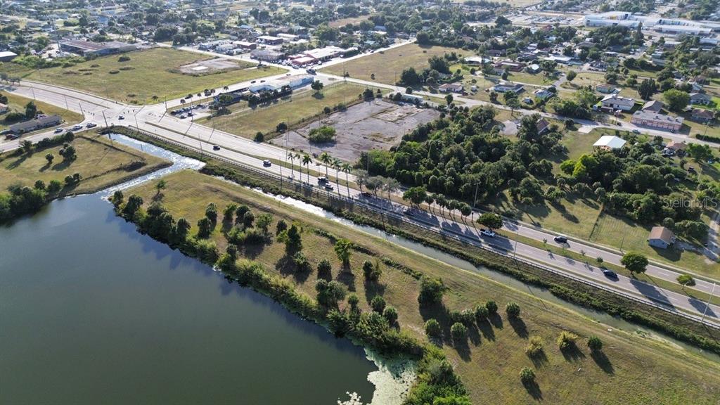 An aerial view shows a road running alongside a canal, a lake, and open land — 3550 S GRIMSLEY COURT, FORT MYERS, FL