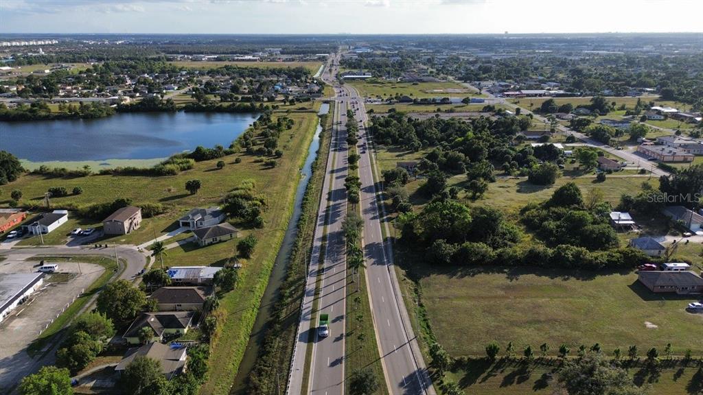 An aerial view shows a divided highway running through a suburban area with a canal — 3550 S GRIMSLEY COURT, FORT MYERS, FL