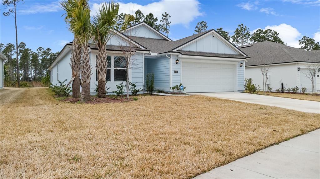 A light blue single-story house with a two-car garage and palm trees in the yard — 7 SUMMERWOOD ROAD N, PALM COAST, FL