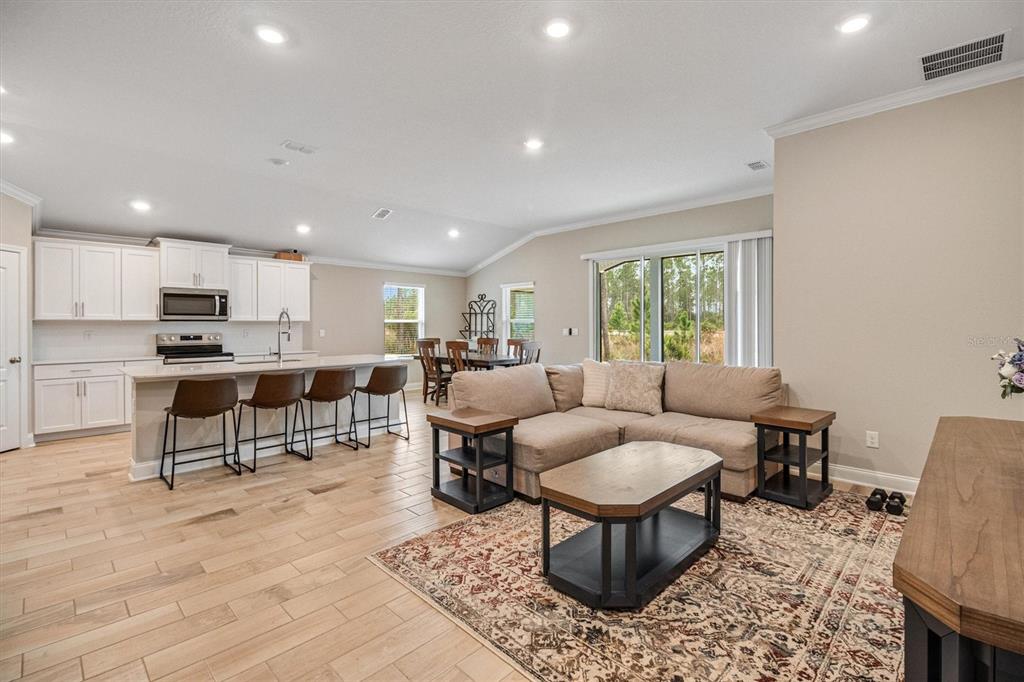 An open-concept living room and kitchen featuring light wood flooring and a large kitchen island — 7 SUMMERWOOD ROAD N, PALM COAST, FL