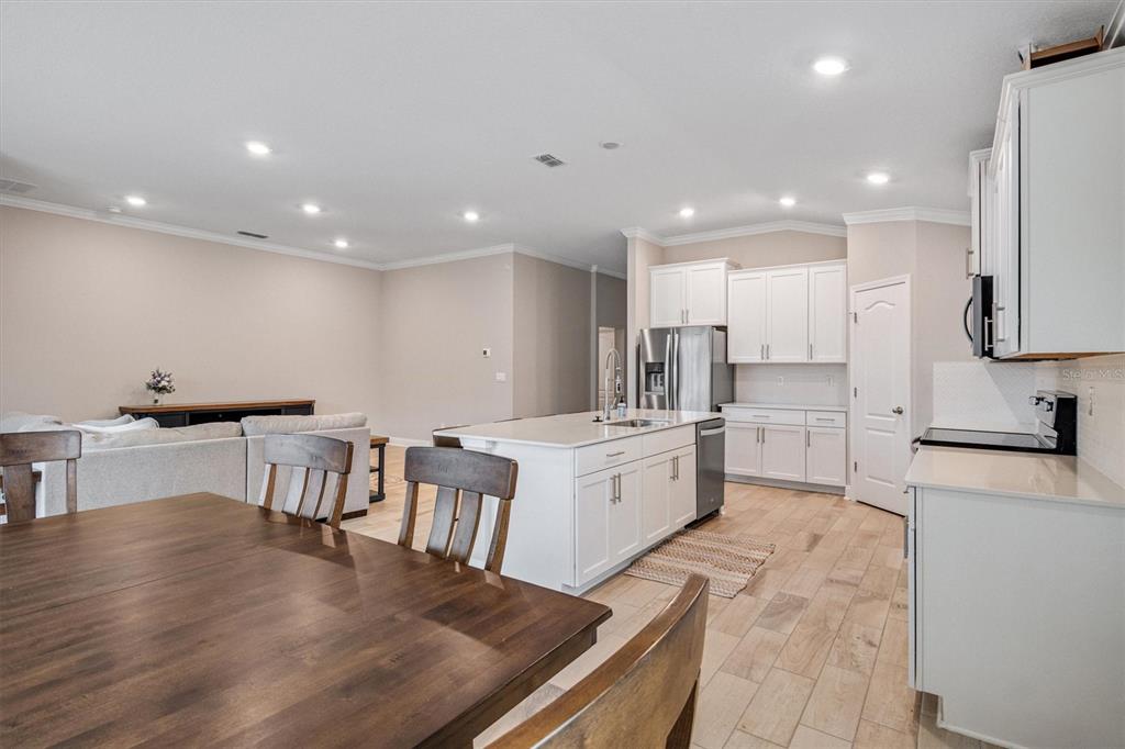 A kitchen with white cabinets and a center island opens to a living area — 7 SUMMERWOOD ROAD N, PALM COAST, FL
