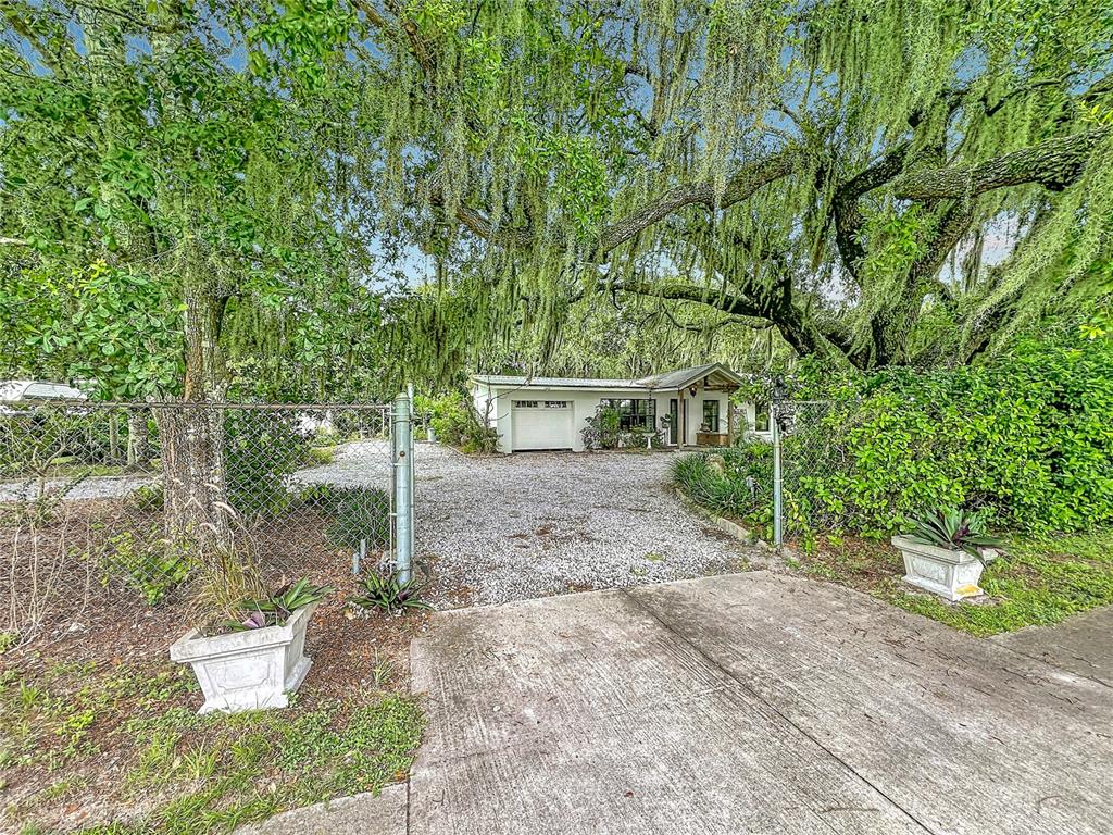 A single-story house with a white exterior and garage sits behind a chain-link fence — 3851 S SANFORD AVENUE, SANFORD, FL