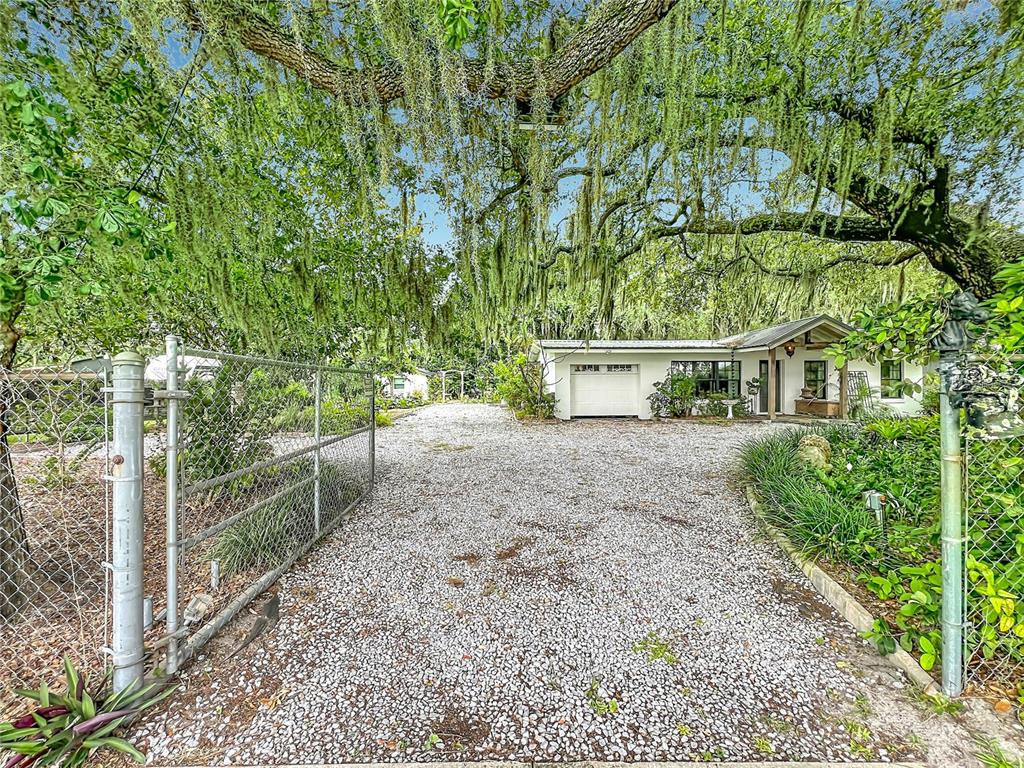 A gravel driveway leads to a white house under a large tree with Spanish moss — 3851 S SANFORD AVENUE, SANFORD, FL