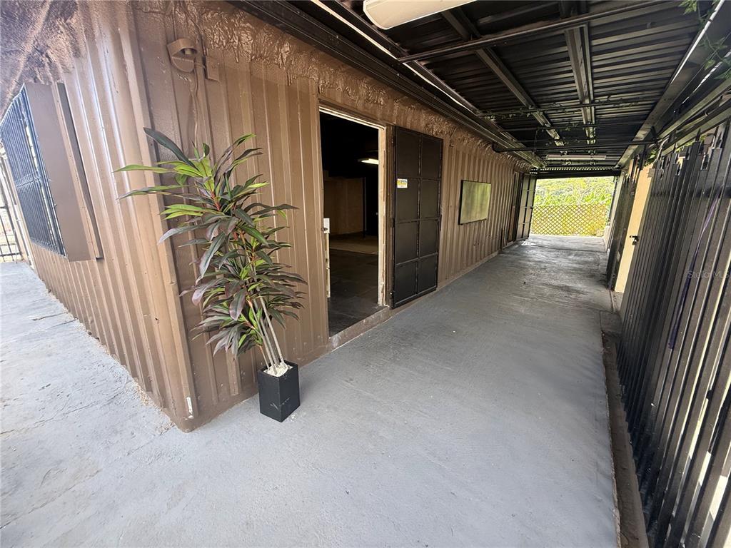 A covered walkway leads to an open doorway of a brown metal-sided building — 116 GUANICA, GUANICA, PR