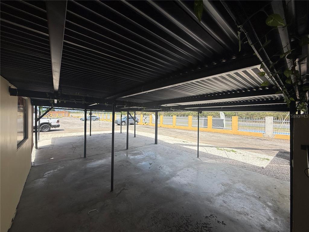 A covered concrete carport features a black corrugated metal roof supported by metal poles — 116 GUANICA, GUANICA, PR