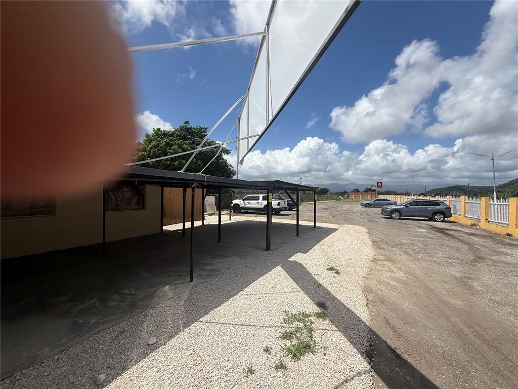A gravel parking area features a covered carport structure and a large billboard frame — 116 GUANICA, GUANICA, PR