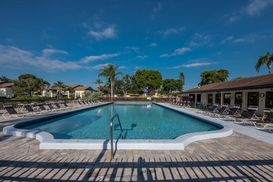 A rectangular outdoor swimming pool surrounded by lounge chairs and a paved patio area — 4765 Sable Pine Circle # B1, West Palm Beach FL 33417, WEST PALM BEACH, FL
