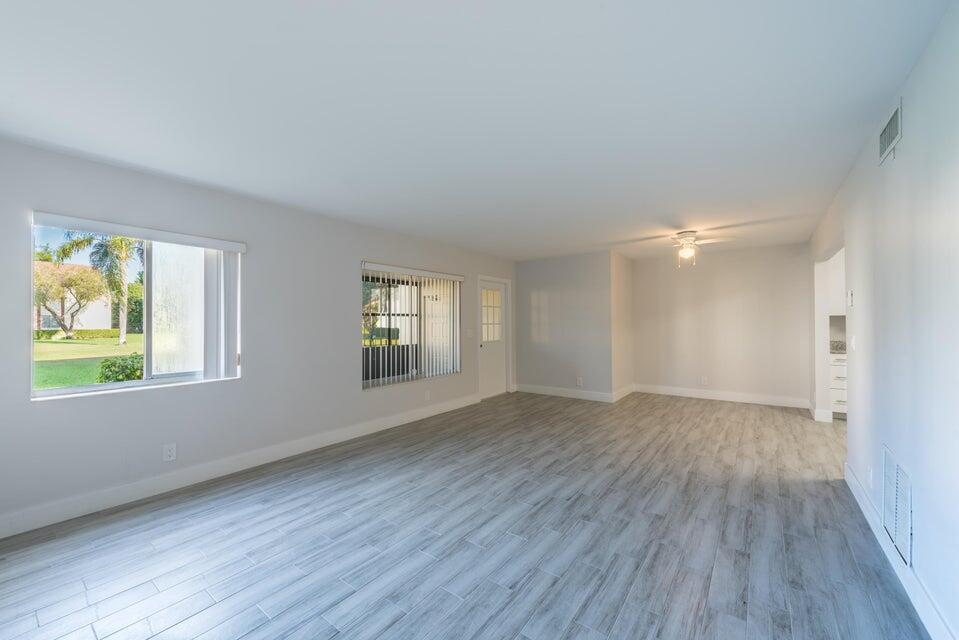 An empty living room with light gray wood-look tile flooring and two windows — 4765 Sable Pine Circle # B1, West Palm Beach FL 33417, WEST PALM BEACH, FL