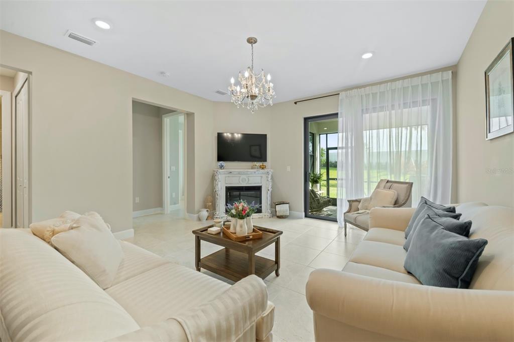 A living room features a fireplace, a television, two sofas, and a sliding glass door — 14586 MOSSY PINE COURT, NOKOMIS, FL