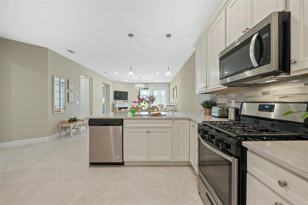 A kitchen with white cabinets, stainless steel appliances, and a view into the living area — 14586 MOSSY PINE COURT, NOKOMIS, FL