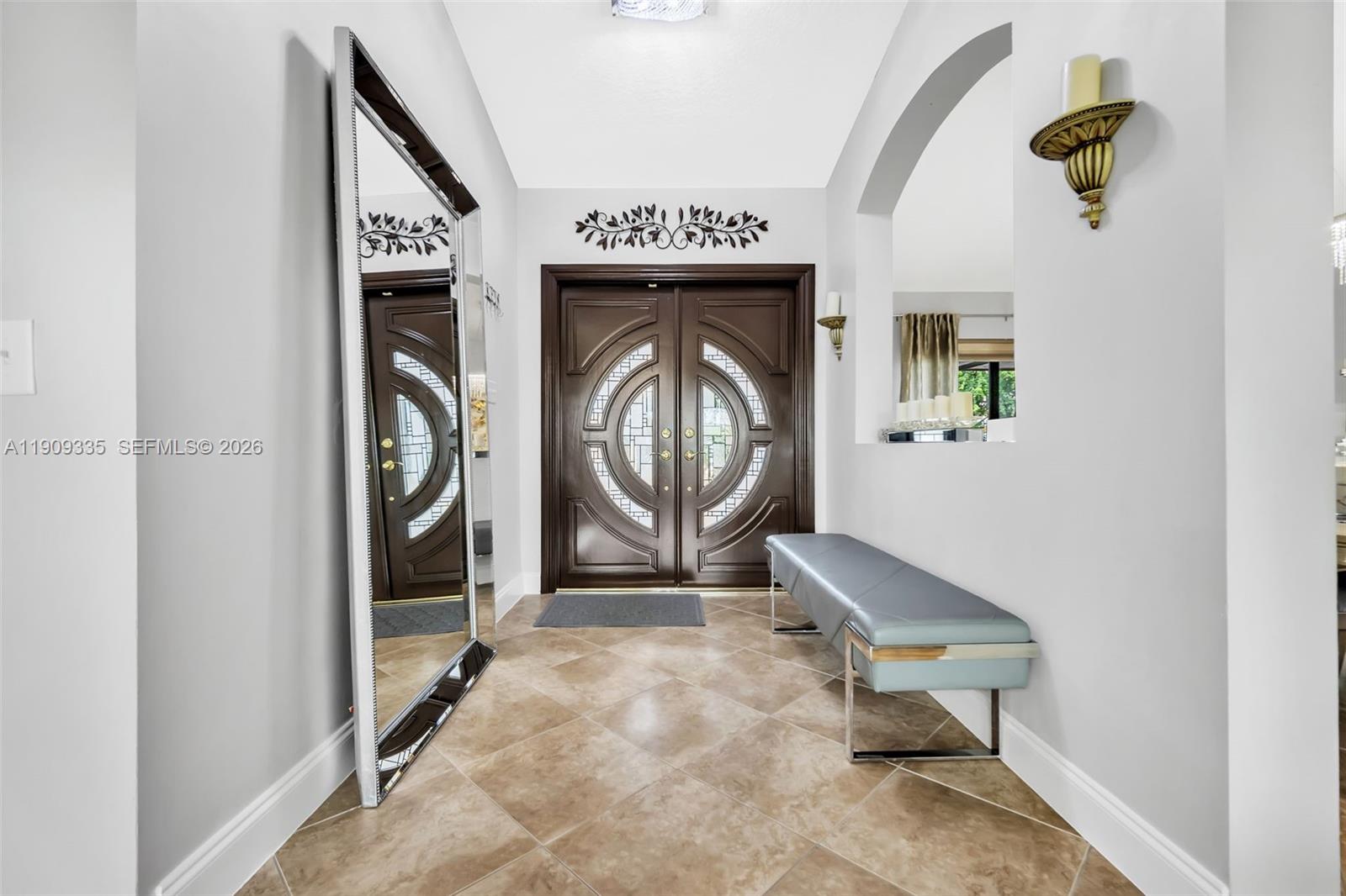 An entryway features a large mirror, a grey bench, and double doors with glass inserts — 15462 SW 115th St, Miami FL 33196, MIAMI, FL