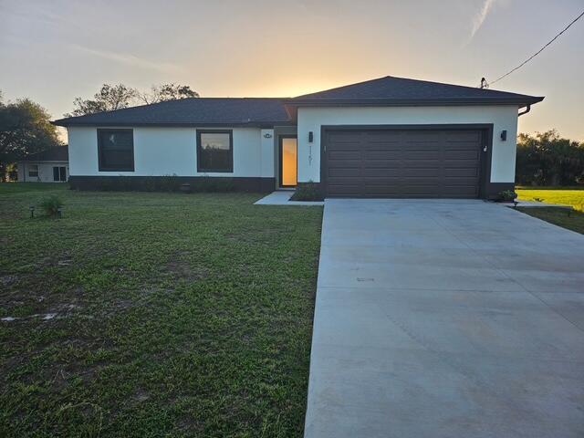 A single-story house with white stucco walls, a dark garage door, and a concrete driveway — 1151 Jabara Circle, FL 33935, FL