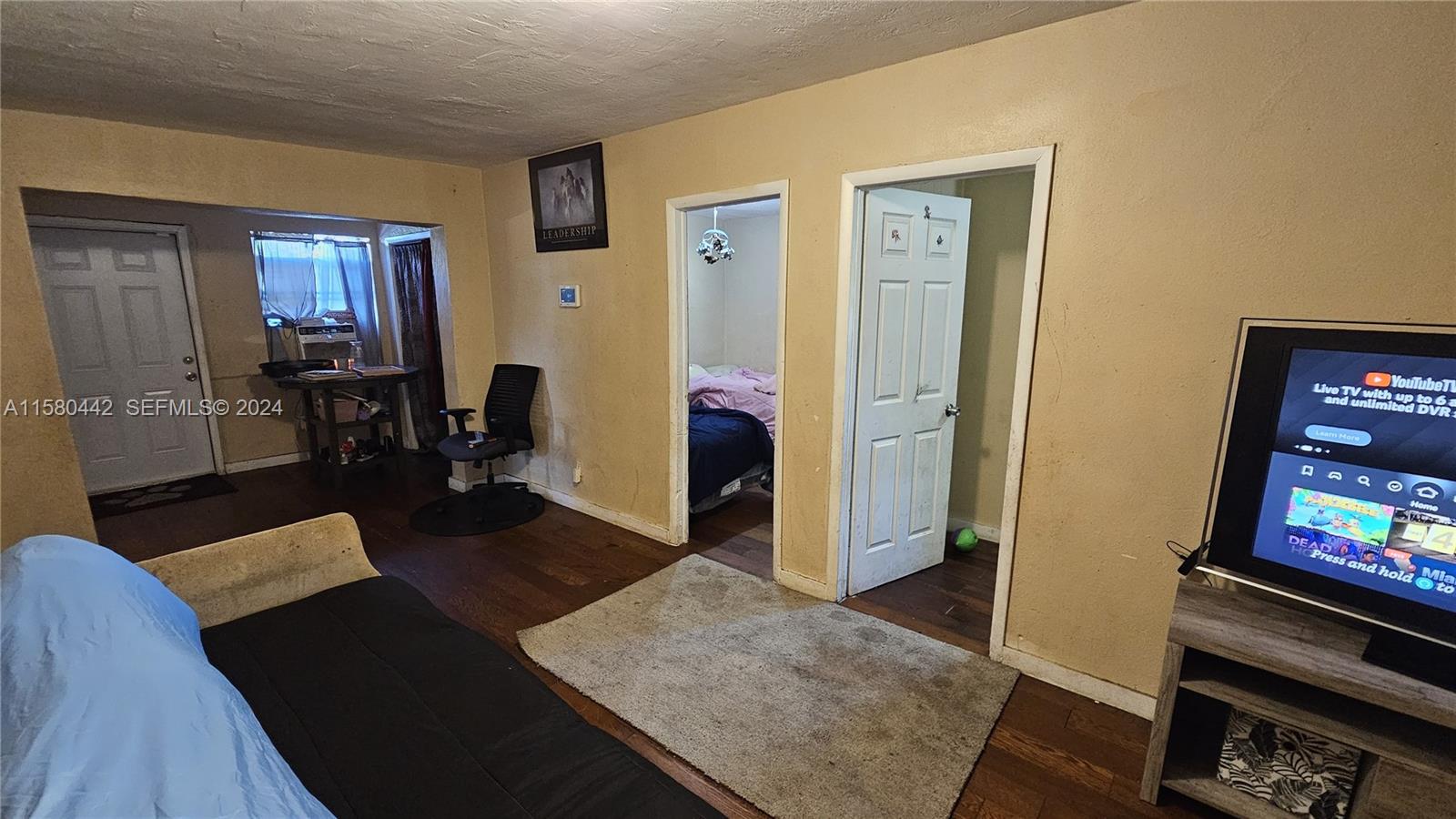 A living room features wood flooring, two doorways leading to bedrooms, and a television — 2114 NW 5th St, Pompano Beach FL 33069, POMPANO BEACH, FL