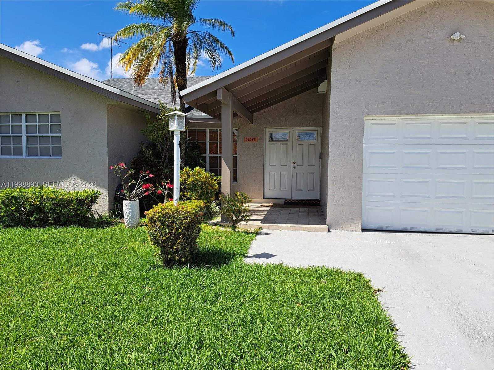 A single-story house features a white garage door, double front doors, and a front lawn — 14527 SW 106th Ter, Miami FL 33186, MIAMI, FL