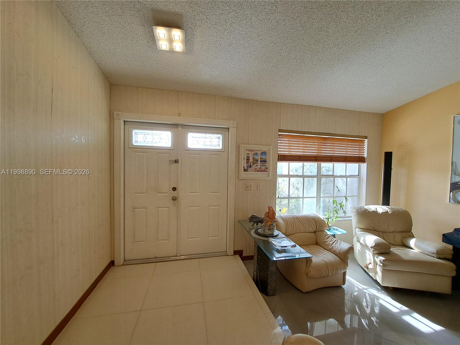 A living room features a double front door, tile flooring, and two beige armchairs — 14527 SW 106th Ter, Miami FL 33186, MIAMI, FL