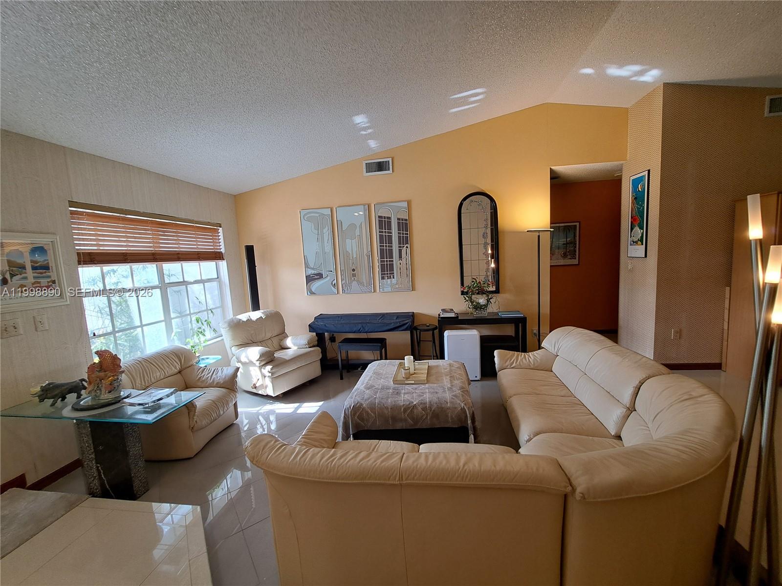 A living room features cream leather sofas, a glass-topped table, and light-colored tile flooring — 14527 SW 106th Ter, Miami FL 33186, MIAMI, FL