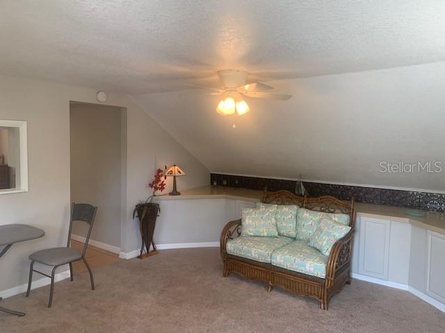 An attic room features a sloped ceiling, a ceiling fan, and a wicker loveseat — 211 W BAY AVENUE UNIT A, LONGWOOD, FL
