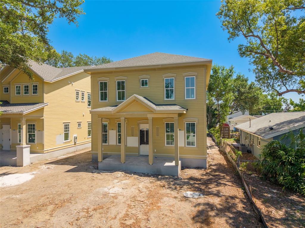 A two-story yellow house with a front porch stands on an unfinished dirt lot — 5326 7TH AVENUE N, ST PETERSBURG, FL