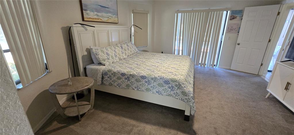 A bedroom features a white bed frame, patterned bedding, a round side table, and carpet — 1290 AKEN STREET, PORT CHARLOTTE, FL