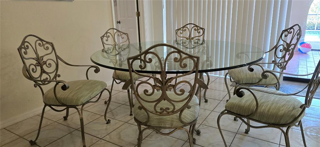 A dining room features a glass-topped table surrounded by five ornate metal chairs — 1290 AKEN STREET, PORT CHARLOTTE, FL