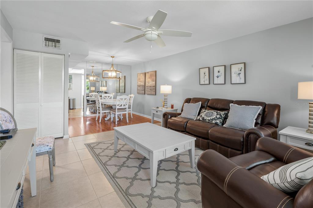 A living room with tile floors, a brown leather sofa, and an adjacent dining area — 7801 11TH STREET N UNIT 302, ST PETERSBURG, FL