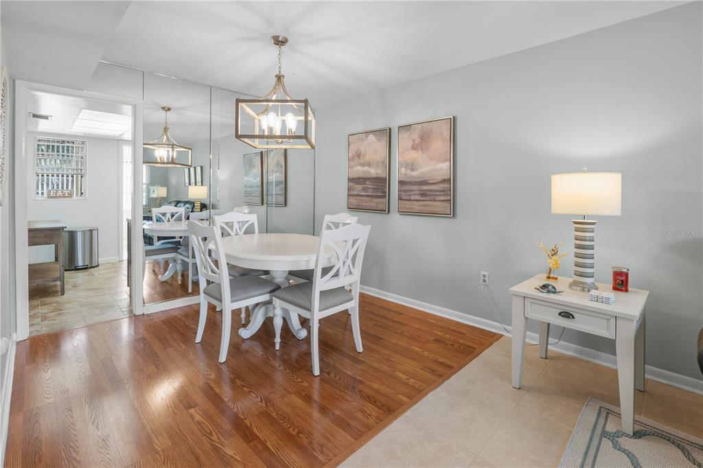 A dining area features a round white table, four chairs, a chandelier, and mirrored walls — 7801 11TH STREET N UNIT 302, ST PETERSBURG, FL