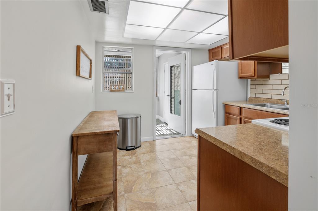 A kitchen features wood cabinets, tan countertops, tile flooring, and a white refrigerator — 7801 11TH STREET N UNIT 302, ST PETERSBURG, FL