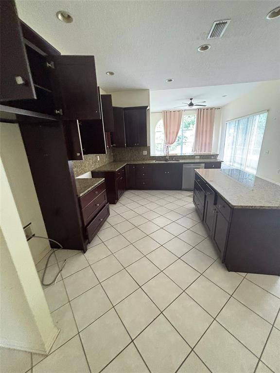 A kitchen features dark wood cabinets, granite countertops, and light-colored tile flooring — 5141 SILVER CHARM TERRACE, ZEPHYRHILLS, FL