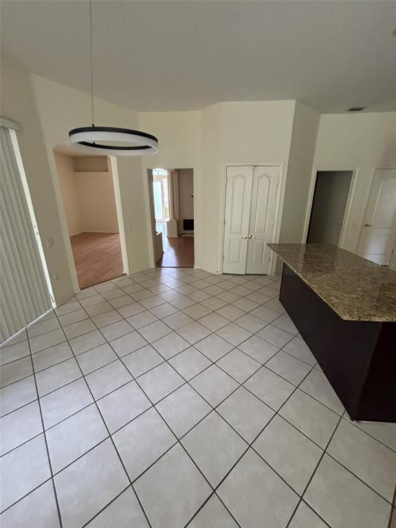 A tiled dining area features a modern circular light fixture and a granite-topped kitchen island — 5141 SILVER CHARM TERRACE, ZEPHYRHILLS, FL