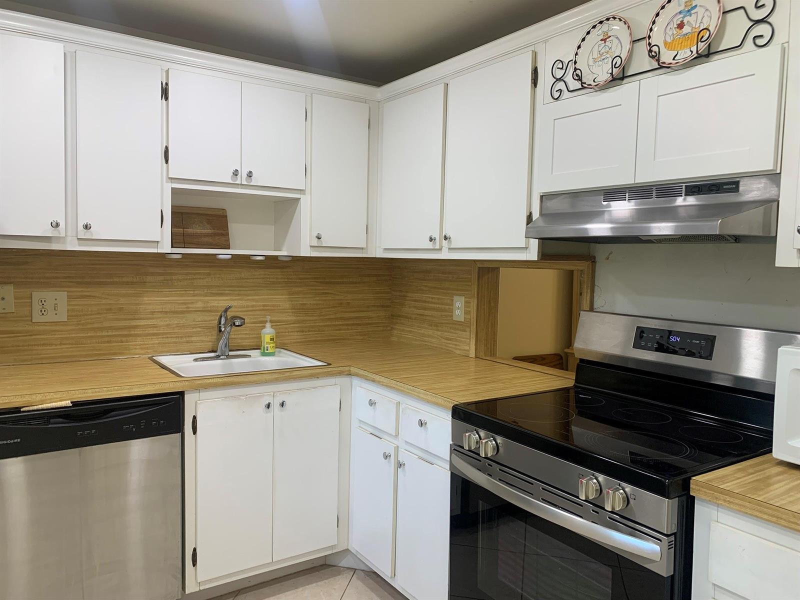 A kitchen with white cabinets, wood-look countertops, a stainless steel stove, and a dishwasher — 3499 Oaks Way # 607, Pompano Beach FL 33069, POMPANO BEACH, FL