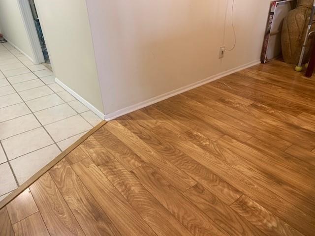 A transition strip separates a tiled floor from a wood-look laminate floor in a room — 3499 Oaks Way # 607, Pompano Beach FL 33069, POMPANO BEACH, FL